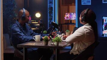 Online show host recording podcast with guest, using analog mixer equipment in home studio living room. Man setting up audio device for live broadcast with woman, ensuring flawless sound quality video