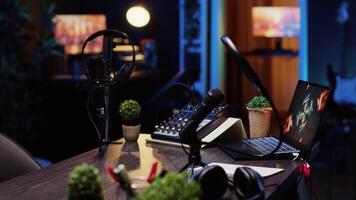 Panning shot of desk in home production studio with podcast equipment technology recording sound and 3D animations running on laptop screen. Professional broadcasting space in apartment video