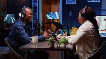 African american influencer recording podcast with guest, using professional equipment in home studio. Joyful host discussing with woman live during broadcasting session for internet show video