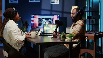 Online show host recording podcast with guest, using audio recording equipment in home studio living room. Happy man and woman laughing together during broadcasting session video