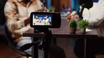 Focus on camera used by podcast host in blurry background to record guest telling interesting story to fans, panning shot. Close up of man and woman talking in studio, filmed by professional equipment video