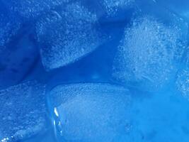 Ice cubes isolated on blue background photo