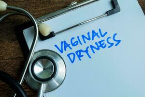 Concept of Vaginal Dryness write on paperwork with stethoscope isolated on wooden background. photo