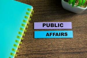 Concept of Public Affairs write on sticky notes isolated on Wooden Table. photo