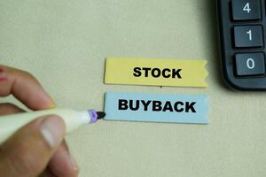 Concept of Stock Buyback write on sticky notes isolated on Wooden Table. photo