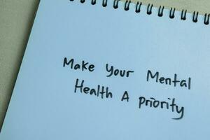 Concept of Make Your Mental Health A Priority write on book isolated on Wooden Table. photo