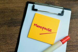 Concept of Menopause write on sticky notes isolated on Wooden Table. photo