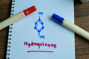 Concept of Hydroquinone molecule write on book isolated on Wooden Table. Structural chemical formula photo