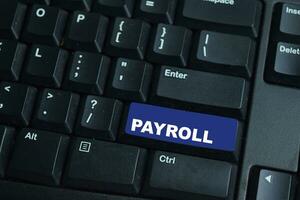 Payroll write on keyboard isolated on laptop background photo