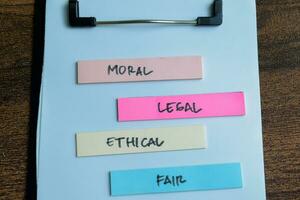 Concept of Moral, Legal, Ethical, Fair write on sticky notes isolated on Wooden Table. photo