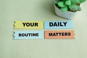 Concept of Your Daily Routine Matters write on sticky notes isolated on Wooden Table. photo