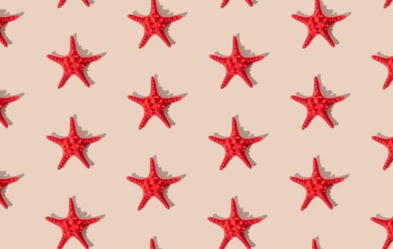 Summer pattern composition made with red starfish on sandy color background. Minimal summer concept. Creative sea star flat lay pattern idea. Top of view. photo