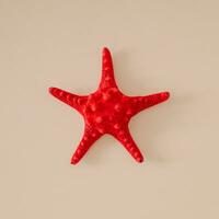 Summer composition made with red starfish on sandy color background. Minimal summer concept. Creative sea star flat lay idea. Top of view. photo