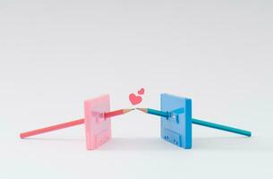 You're the pencil to my cassette tape. Old pink and blue audio cassette tapes and pencils kissing. Minimal love concept. Creative cassette tape idea. Retro love aesthetic background. Retro nostalgia. photo