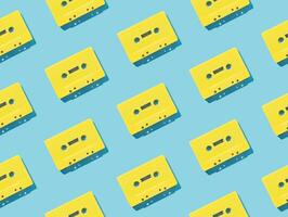 Pattern made with retro yellow audio cassette tapes on light blue background. Creative concept of retro technology. 80's aesthetic. Vintage audio cassette tape pattern idea. Retro nostalgia. Flat lay. photo