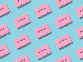 Pattern made with retro pink audio cassette tapes on light blue background. Creative concept of retro technology. 80's aesthetic. Vintage audio cassette tape pattern idea. Retro nostalgia. Flat lay. photo