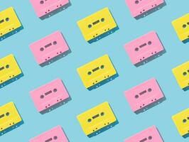 Pattern of retro pink and yellow audio cassette tapes on  blue background. Creative concept of retro technology. 80's aesthetic. Vintage audio cassette tape pattern idea. Retro nostalgia. Flat lay. photo