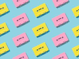 Pattern of retro pink and yellow audio cassette tapes on  blue background. Creative concept of retro technology. 80's aesthetic. Vintage audio cassette tape pattern idea. Retro nostalgia. Flat lay. photo