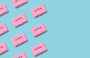 Pattern made with retro pink audio cassette tapes on light blue background. Creative concept of retro technology. 80's aesthetic. Vintage audio cassette tape pattern idea. Retro nostalgia. Flat lay. photo
