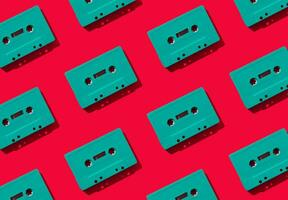 Pattern made with retro green audio cassette tapes on red background. Creative concept of retro technology. 80's aesthetic. Vintage audio cassette tape pattern idea. Retro nostalgia. Flat lay. photo