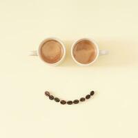 Layout of smiley emoticon made with coffee cups and coffee beans on pastel background. Minimal coffee concept. Creative positive thinking and good mood idea composition. Coffee aesthetic. Flat lay. photo