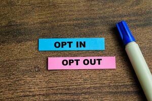 Concept of Opt in and Opt Out write on sticky notes isolated on Wooden Table. photo