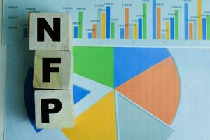 Concept of The wooden Cubes with the word NFP - Non Farm Payrolls on wooden background. photo