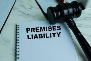 Concept of Premises Liability write on book with gavel isolated on Wooden Table. photo