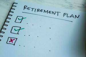 Concept of Retirement Plan write on book. Supported by an additional services isolated on Wooden Table. photo