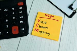 Concept of VSM - Value Stream Mapping write on sticky notes isolated on Wooden Table. photo