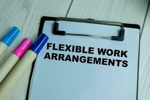 Concept of Flexible Work Arrangements write on paperwork isolated on wooden background. photo