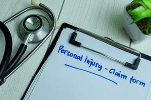 Concept of Personal Injury - Claim Form write on paperwork with stethoscope isolated on wooden background. photo