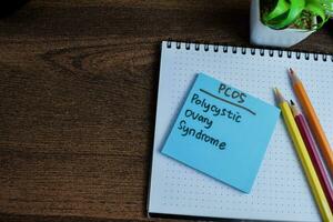 Concept of PCOS - Polycystic Ovary Syndrome write on sticky notes isolated on Wooden Table. photo