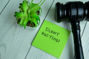 Concept of Silent Auction write on sticky notes with gavel isolated on Wooden Table. photo