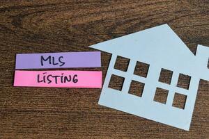 Concept of MLS Listing write on sticky notes isolated on Wooden Table. photo