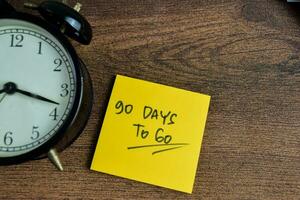 Concept of 90 Days To Go write on sticky notes isolated on Wooden Table. photo