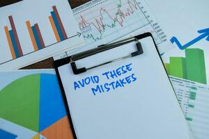 Concept of Avoid These Mistakes write on paperwork isolated on wooden background. photo