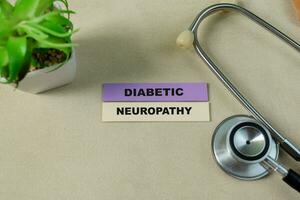 Concept of Diabetic Neuropathy write on sticky notes with stethoscope isolated on Wooden Table. photo