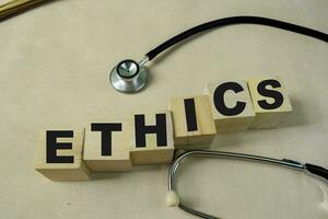 Concept of The wooden Cubes with the word Ethics with stethoscope on wooden background. photo