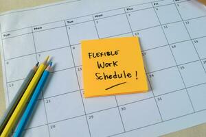 Concept of Flexible work schedule write on sticky notes isolated on Wooden Table. photo