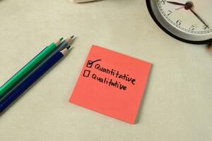 Concept of Quantitative or Qualitative write on sticky notes isolated on Wooden Table. photo