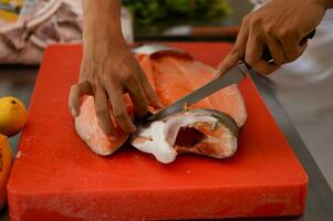 Fresco salmón filete de cerca en blanco corte tablero mesa mientras fileteado salmón barriga por cocinero en Cocinando habitación foto