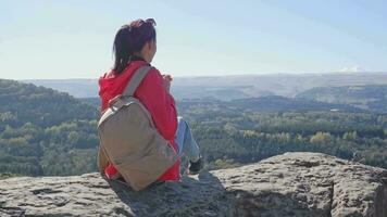 posterior ver de un hembra viajero con un mochila en su espalda en un montaña parte superior en un soleado día admirativo el paisaje de el Cáucaso montañas. hermosa ver de el montaña paisaje video