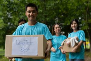 Happy young Asian students diverse volunteers hold donate box and toys for charity to share children and orphanages, a charity for sustainability. Volunteer work lifestyle and social cooperation photo