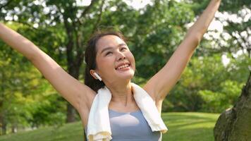 Portrait young asian woman attractive smiling and use white towel resting after workout. Smiling sporty young woman working out outdoors and looking at camera. Healthy lifestyle well being wellness photo