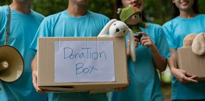 Happy young Asian students diverse volunteers hold donate box and toys for charity to share children and orphanages, a charity for sustainability. Volunteer work lifestyle and social cooperation photo