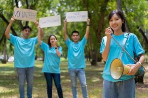 Happy young Asian students diverse volunteers hold a campaign sign for cleaning in the park, The concept of environmental conservation on world environment day, recycling, charity for sustainability. photo