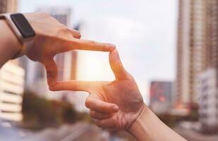 Businesswoman hand gesture focusing on search frame with tall buildings, business city area showing view of approaching target. Concept of vision and strategic planning photo