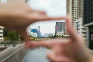 Gesture of hand creates a frame looking through the focus of the large business district capital city clear background image. concept of business setting clear goals and vision. photo