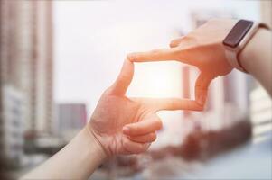 Businesswoman hand gesture focusing on search frame with tall buildings, business city area showing view of approaching target. Concept of vision and strategic planning photo